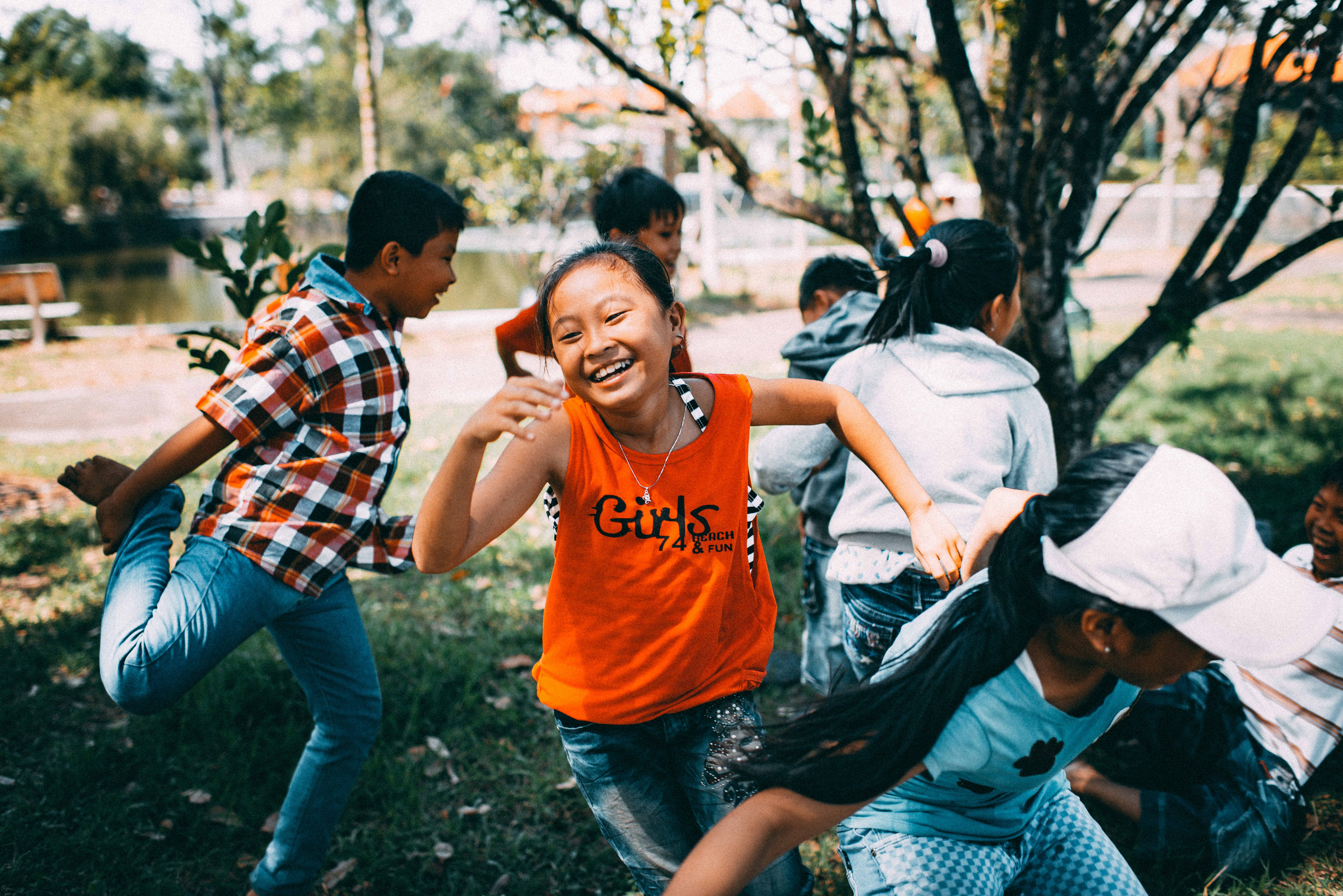 Children laughing and running together while playing outdoors in a park