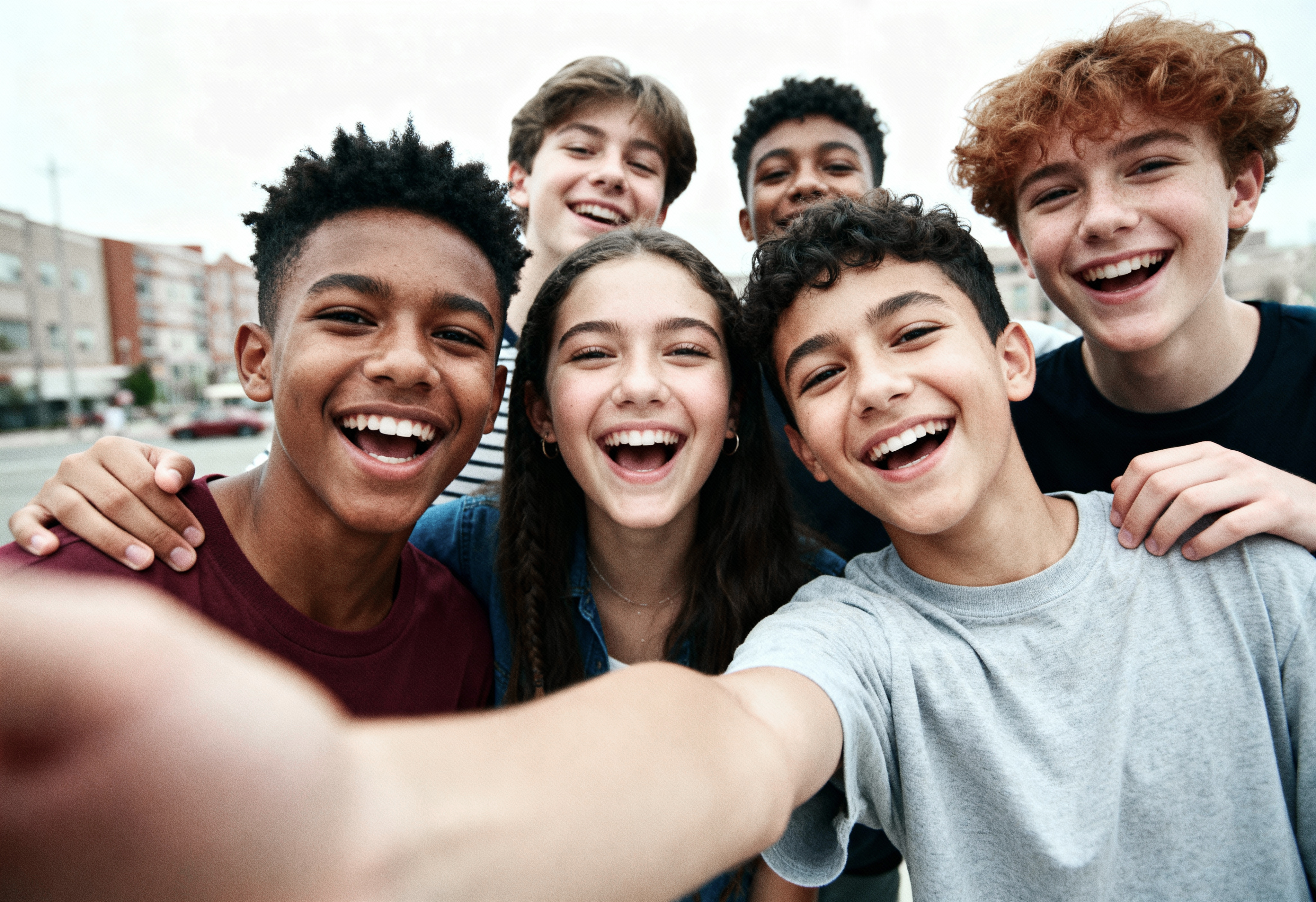 A group of teenagers laughing together in a selfie outdoors