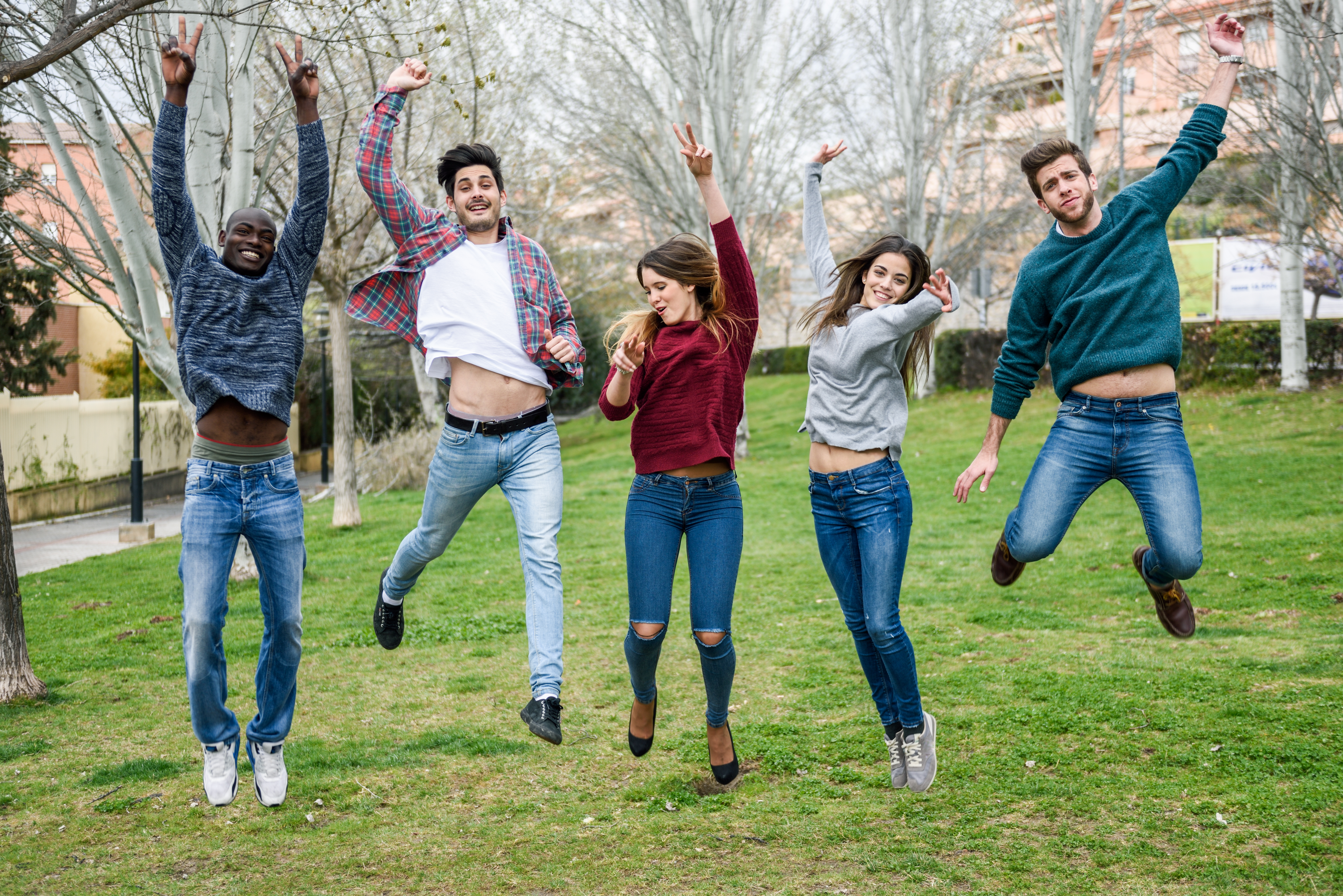 A group of young people jumping in the air together in a park